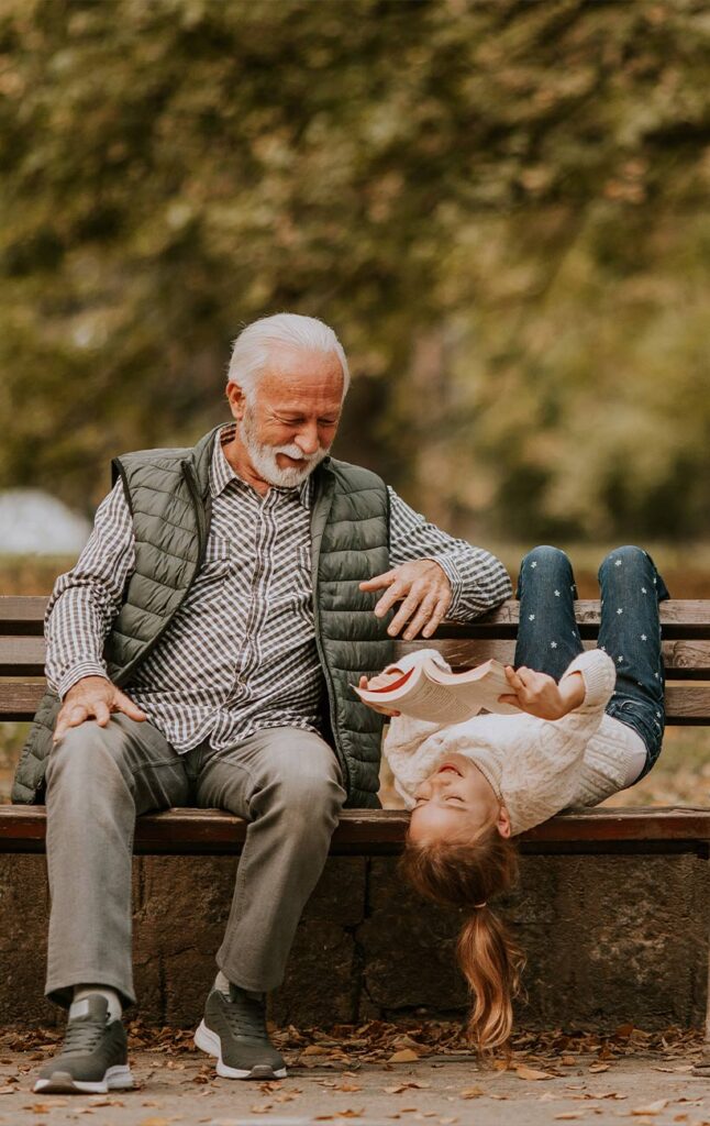 grandpa sitting on park bench with his granddaughter reading annuities