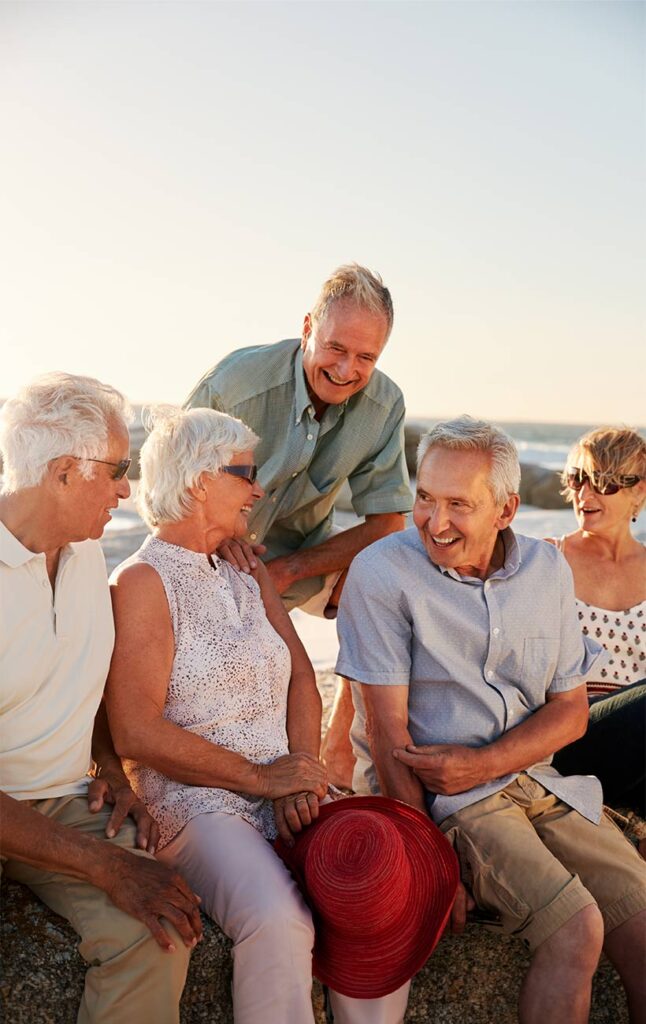 senior friends sitting on rocks by the beach retirement future